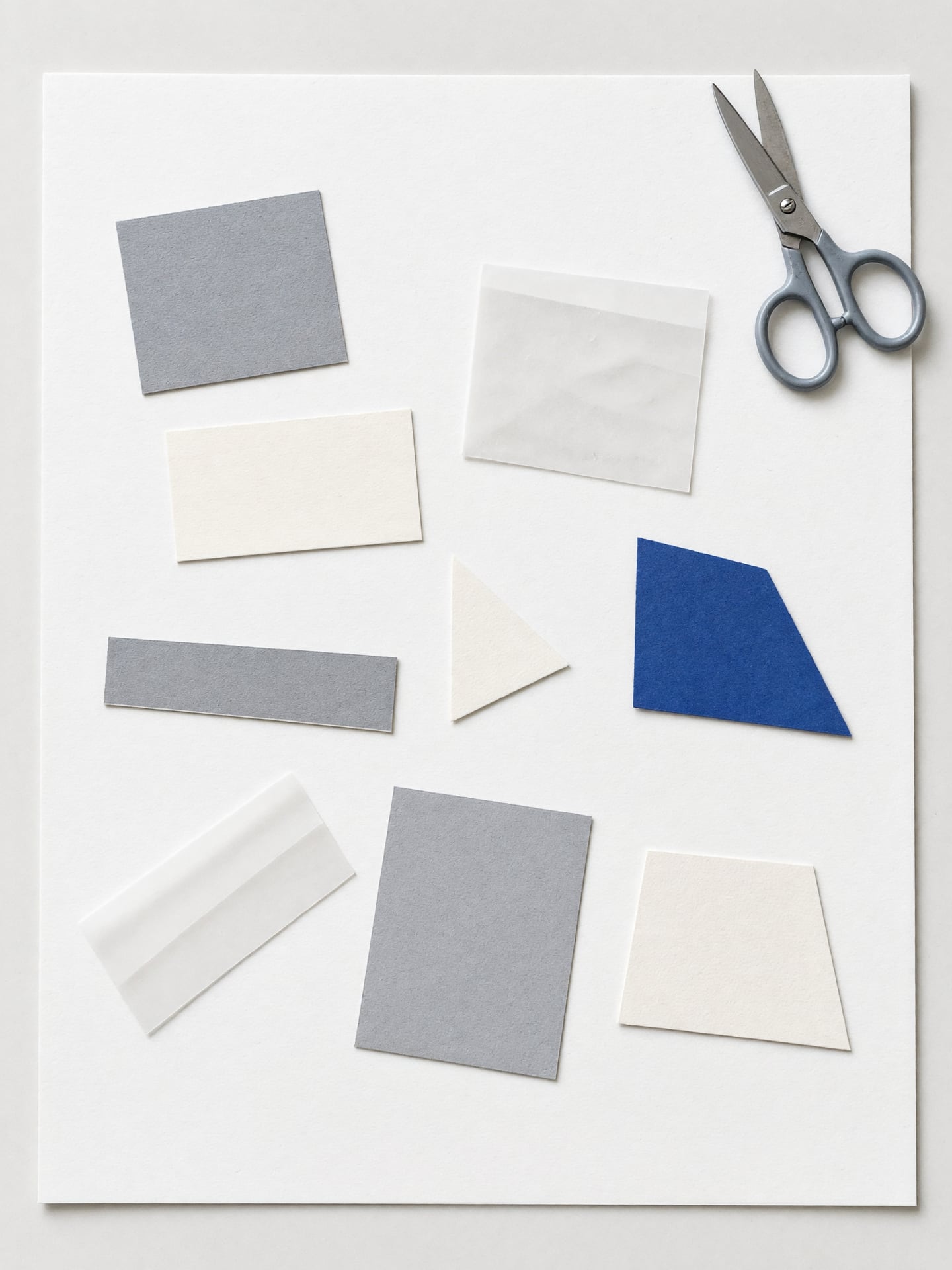 Draufsicht auf einen Tisch mit Papierausschnitten, Transparentpapier und einem blauen Reststück.