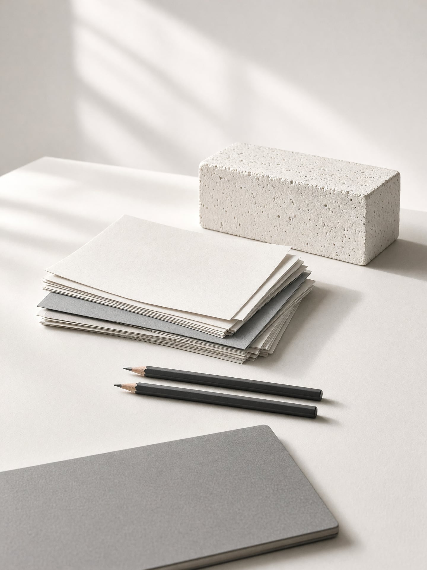 Werkbank im Atelier mit Papierbögen, Graphitstiften und einer hellen Gipsform.